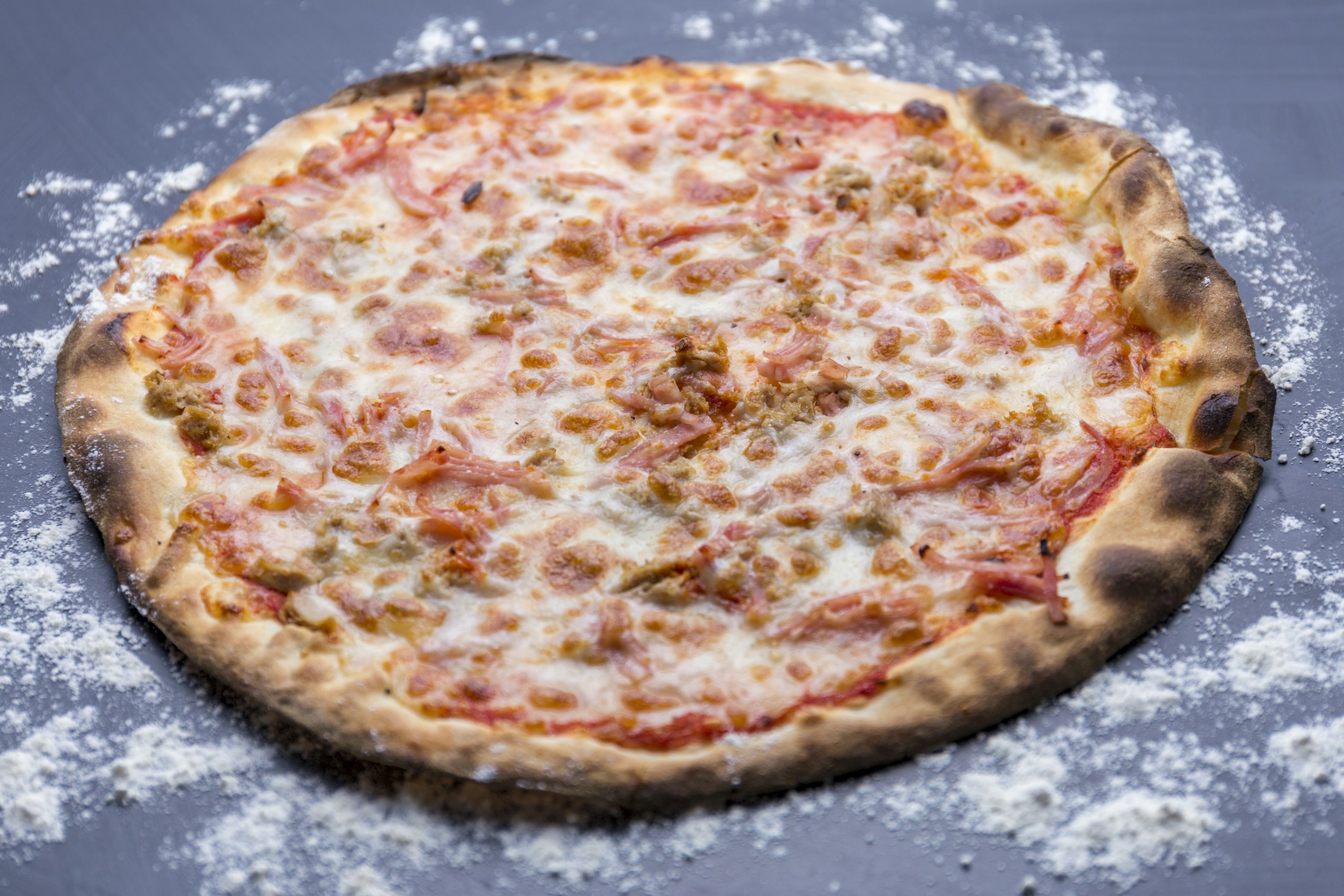 Fotografia ilustrativa de pizza assada sobre uma superfície cinza.